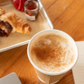 Cup of coffee with a tray of pastries on a wooden table