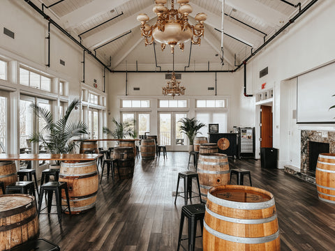 White event space with tall ceilings, chandelier, and barrel tables in Norfolk, VA