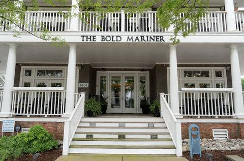 Front of a building with 'The Bold Mariner' sign on a white porch.