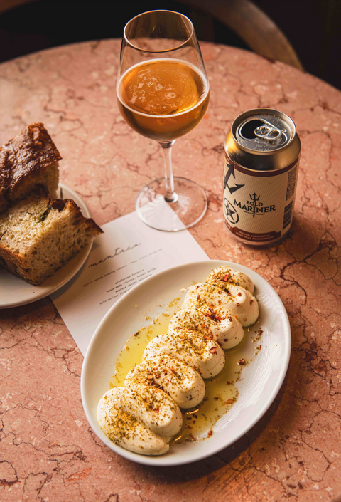 Dish of food, glass of beer, and can on a textured surface