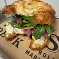 Chicken salad andwich with croissant bread on paper and tray