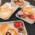 Pastries on trays with strawberries and jam on a dark surface