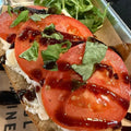 Tomato toast with arugula and balsamic glaze on a metal tray.