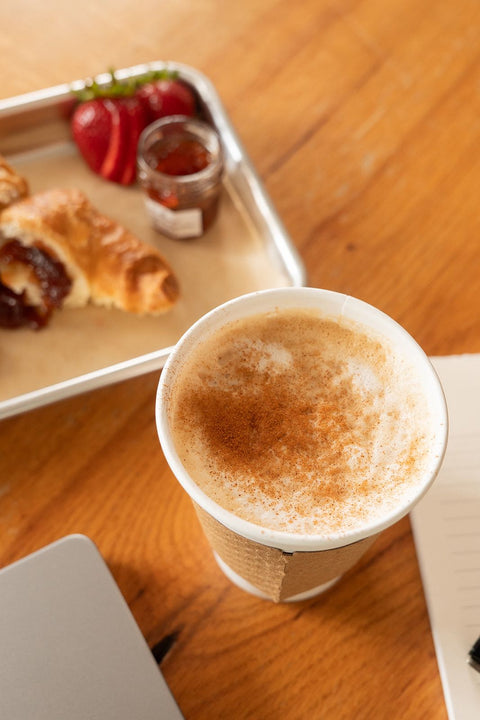 Cup of coffee with a tray of pastries on a wooden table