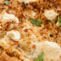 Close-up of a pizza with cheese and basil leaves on a wooden surface