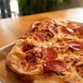 Pepperoni pizza on a wooden table with a blurred background