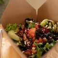 Salad in a cardboard box on a wooden table