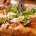 Close-up of a pizza with arugula and cheese on a wooden surface