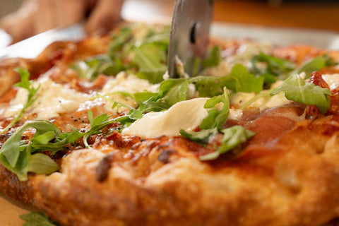 Close-up of a pizza with arugula and cheese on a wooden surface