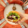 Hand holding a burger in front of an orange life preserver with 'COMFORT' text.