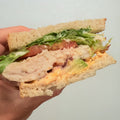 Hand holding a chicken sandwich on a plain background