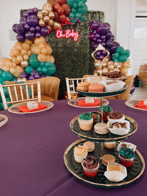 Decorative table setting with balloons, a cake stand with cupcakes, and a 'Oh Baby!' sign.
