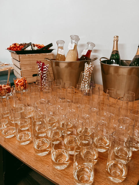 Table set up for a party with glasses, bottles, and snacks.