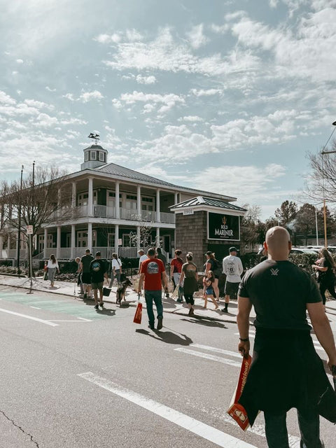 People walking on a street with a building labeled 'Bold Mariner' in the background.