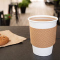 Coffee cup with a brown sleeve and white lid on a table with a blurred background