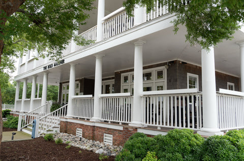 Two-story Bold Mariner building with a large white porch and trees in the background