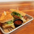 Sandwich on a tray with a side of ketchup on a wooden table